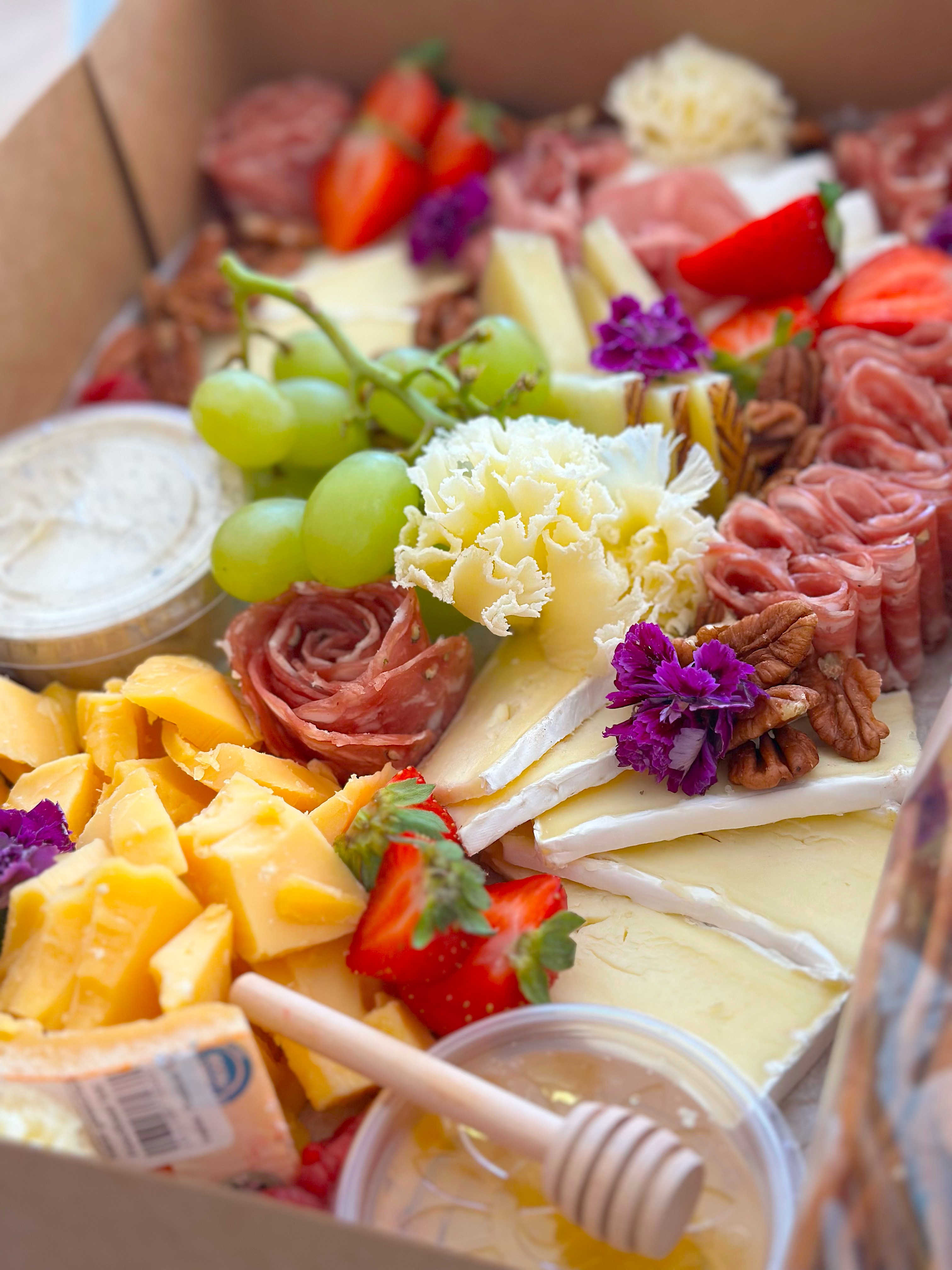 Borrelbox met kaas, fruit, vleeswaren en bloemen