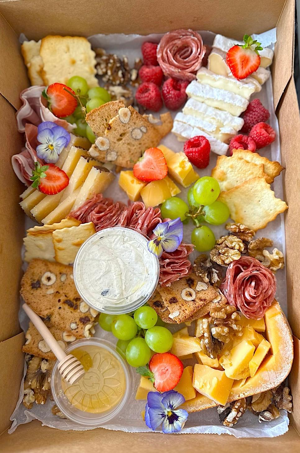 Borrelbox van bovenaf met kazen, fruit en vleeswaren